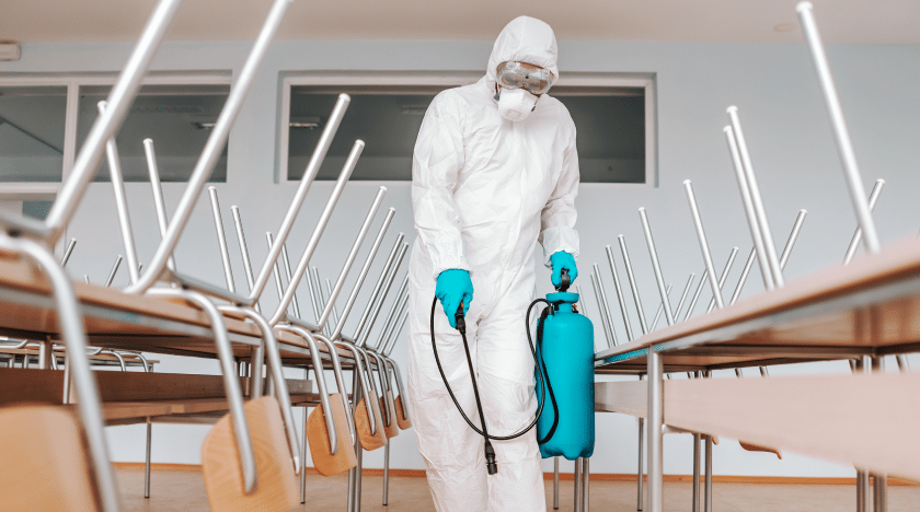40aff4d5-man-sterile-uniform-with-gloves-mask-holding-sprayer-spraying-with-disinfectant-floor-classroom-1.png