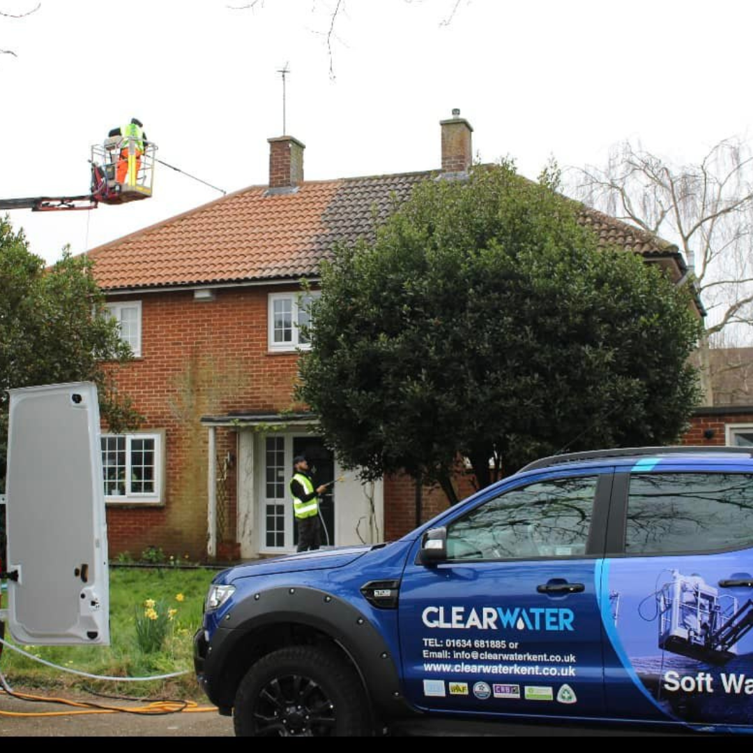 Technicians performing soft wash roof cleaning on a residential property, Clearwater Kent branded vehicle in foreground, showcasing professional cleaning services in Gillingham.