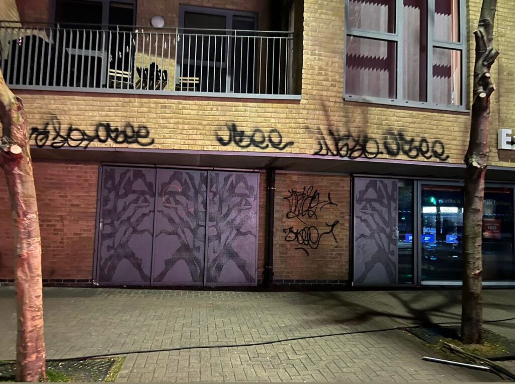 Graffiti on a brick building exterior, featuring multiple tags and markings, highlighting the need for professional graffiti removal services in Kent.