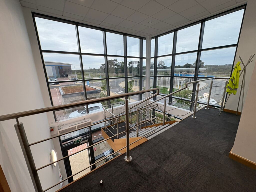Modern commercial building interior with large windows, showcasing a clean and bright staircase leading to the entrance, emphasizing professional cleaning services in Kent.